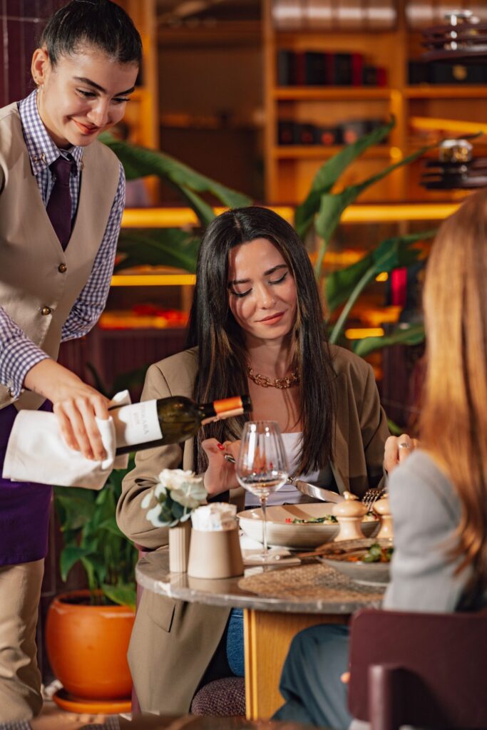 Waiter serving wine to guests at the table