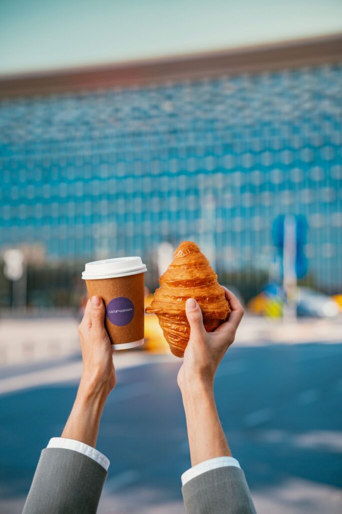 Hands holding coffee and a croissant in Taksim Square