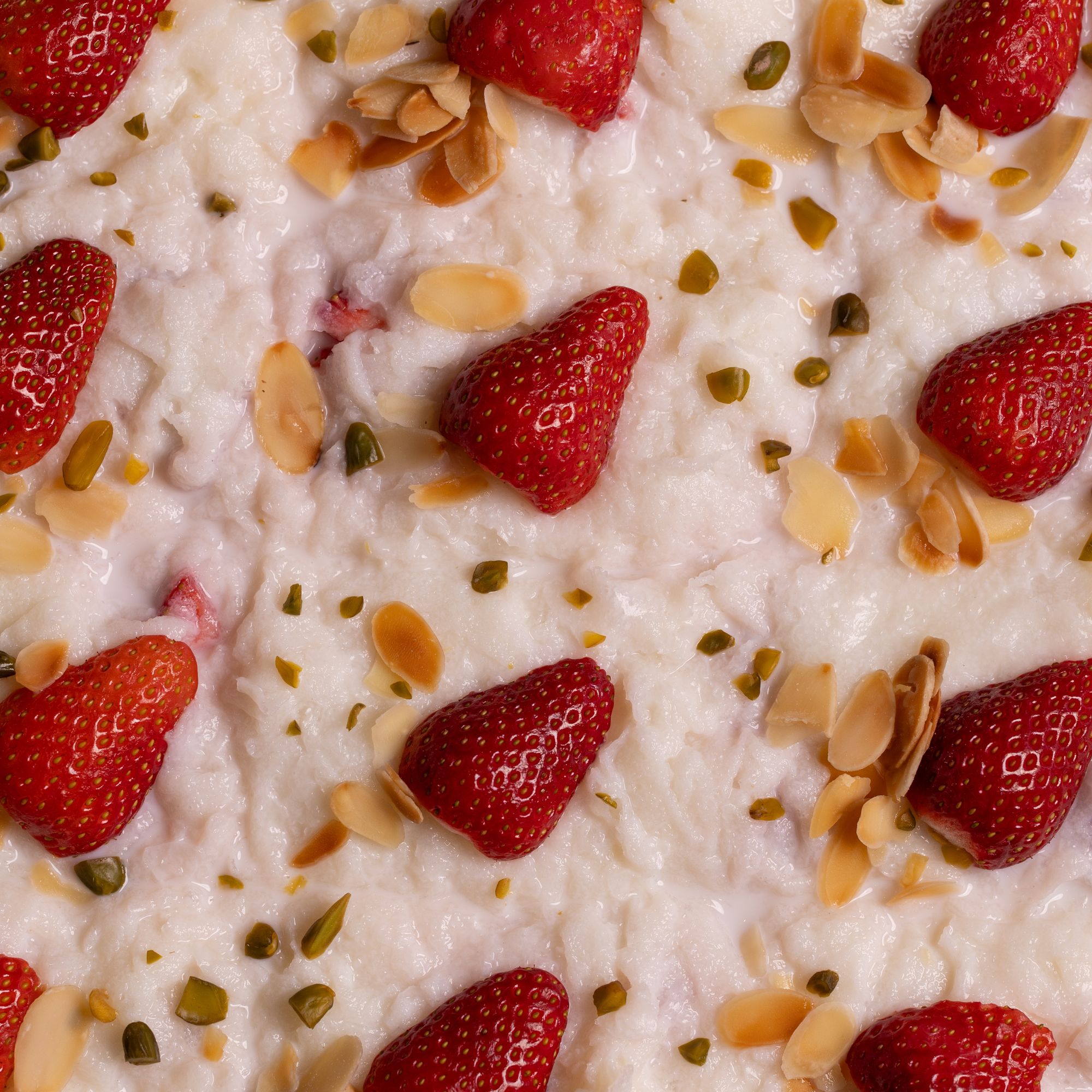 Milk pudding topped with strawberries, almonds and pistachios